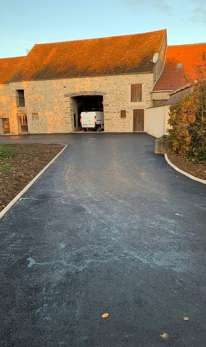 Allée en enrobé noir devant une bâtisse ancienne